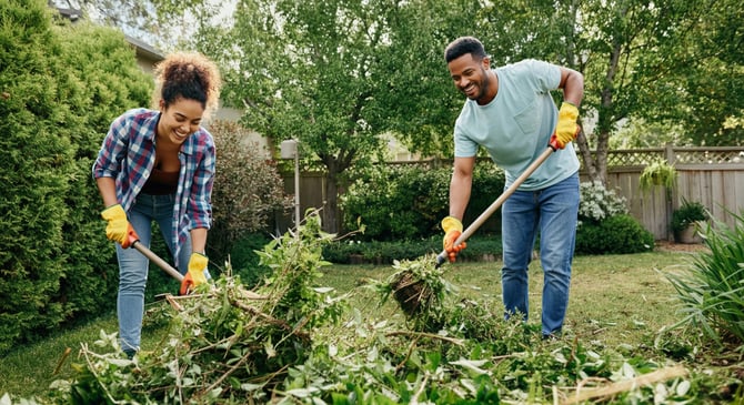 A couple cleaning up their backyard from debris and weeds
