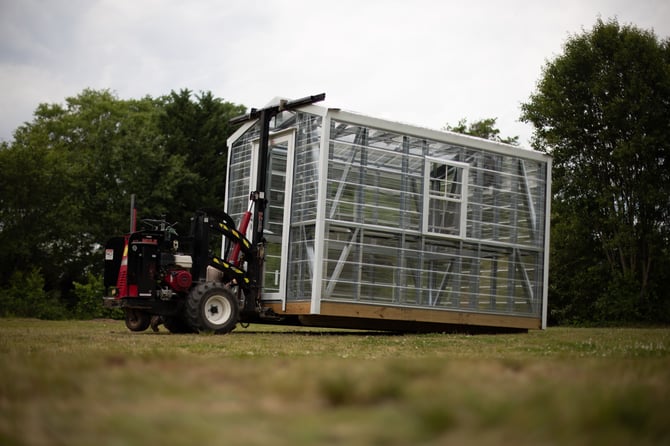 A greenhouse being delivered by a forklift